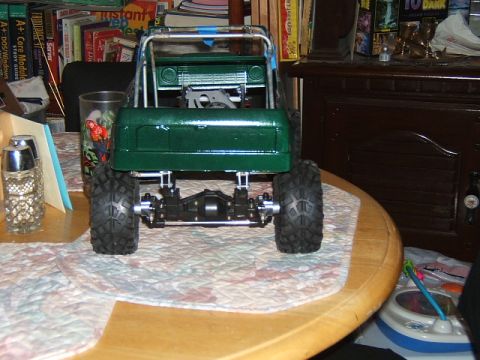 1988 Ford Bronco - Rear view of a green RC crawler with prominent off-road tires and suspension details.