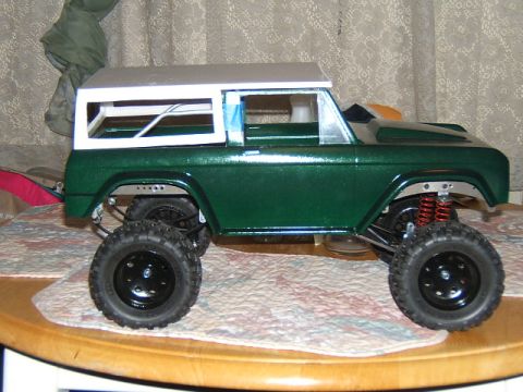 1988 Ford Bronco - This green toy truck features a white roof and oversized tires, presented from a side profile.