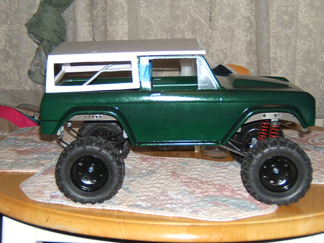 Green toy truck with white roof and large tires, side view