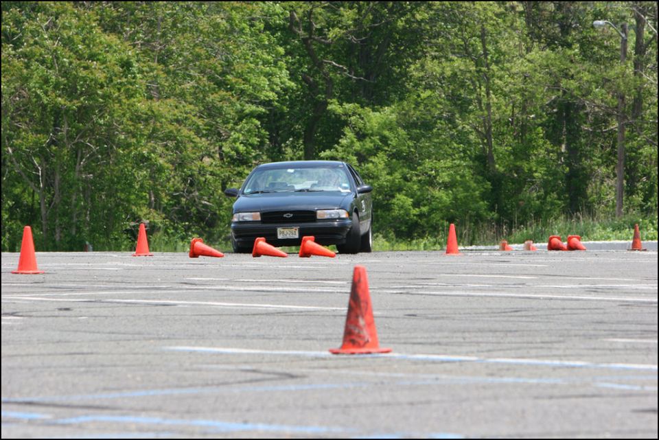dark sedan on a paved lot surrounded by orange cones