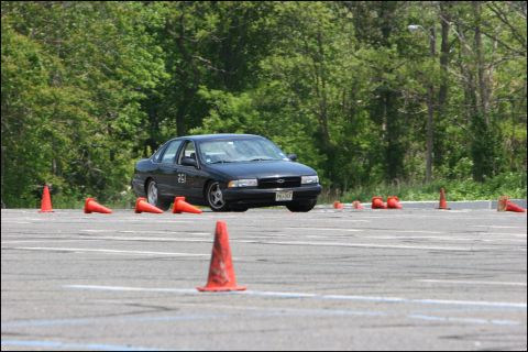 2001 Mercury Grand Marquis - A dark sedan navigates an autocross course marked by orange cones.