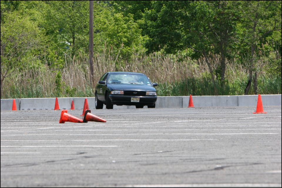 Dark sedan navigating an autocross course with orange cones