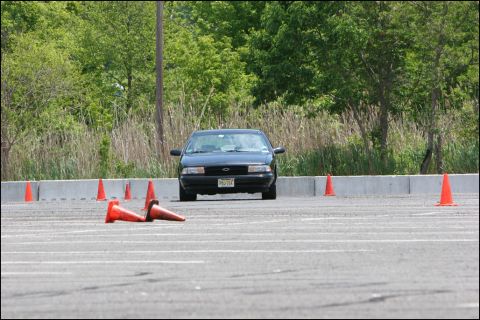 2001 Mercury Grand Marquis - A black sedan navigates a course marked by orange cones on a sunny day.