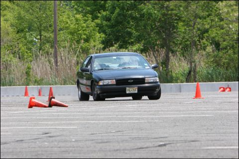 2001 Mercury Grand Marquis - A black sedan is shown on a paved track, maneuvering around orange cones during a driving event.