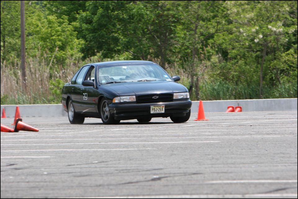 Black sedan with number 25 on the door, driving on a track with orange cones