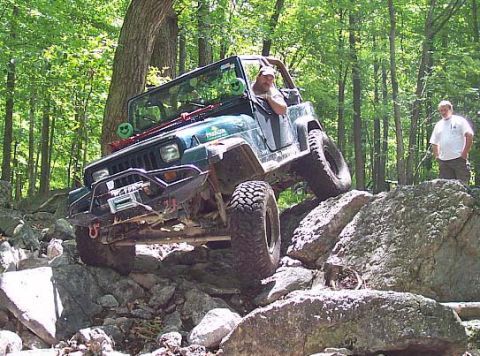 2003 Jeep Wrangler - This Jeep Wrangler is navigating a challenging rocky terrain in a wooded area.