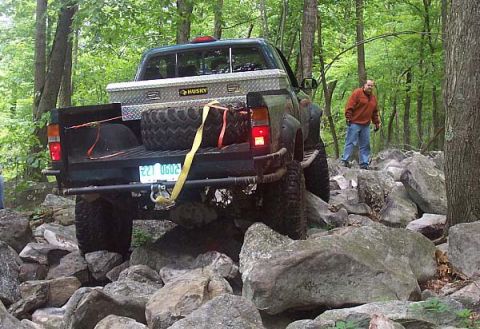 2003 Jeep Wrangler - A pickup truck is shown on a challenging rocky terrain, with a person standing nearby.