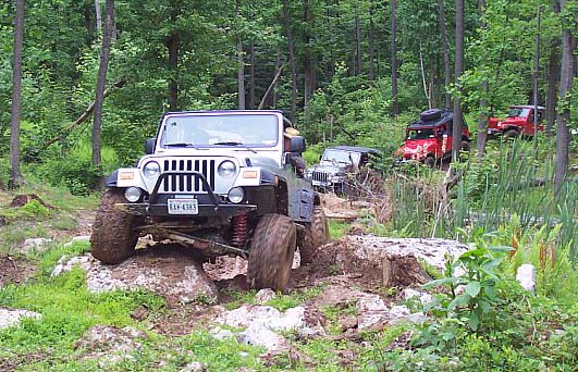 2003 Jeep Wrangler navigating rocky terrain with other Jeeps behind