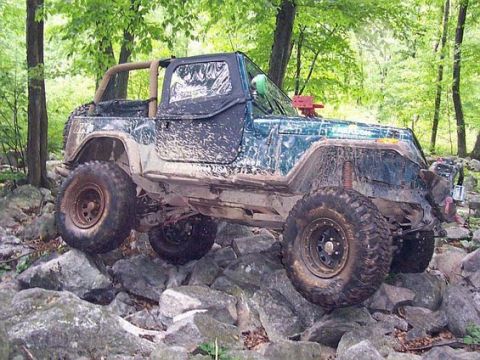 2003 Jeep Wrangler - This modified Jeep Wrangler navigates a challenging rocky terrain in a forest setting.