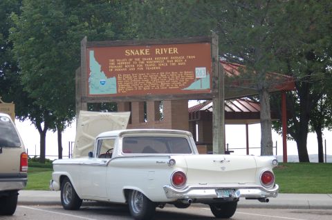 1967 Ford Ranchero - A white 1959 Ford Ranchero pickup truck is parked with its hood open near a Snake River historic passage sign.