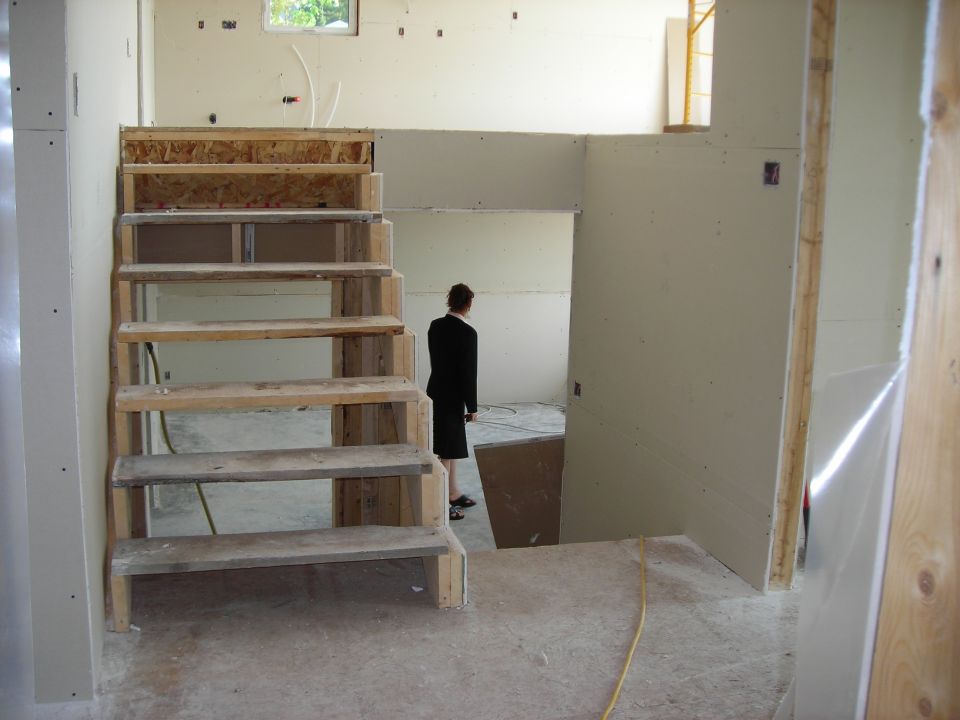 Interior construction scene with unfinished staircase and a person in a suit
