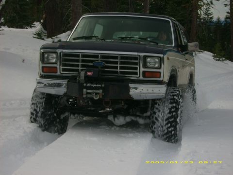 1986 Ford Bronco - This Ford Bronco is navigating a snowy trail, equipped with a winch for off-road challenges.