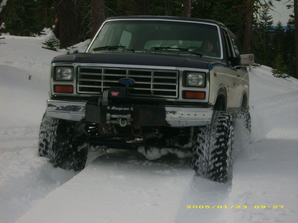 Ford Bronco driving through snow with large tires. Has a winch and Snap-on logo on the front