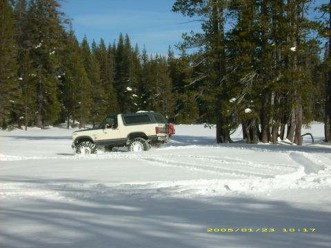 1986 Ford Bronco - 1986 Ford Bronco navigating through a snowy landscape with tire tracks visible.