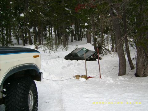 1986 Ford Bronco - A vehicle is stuck in the snow, with another vehicle nearby appearing to be stuck in trees.