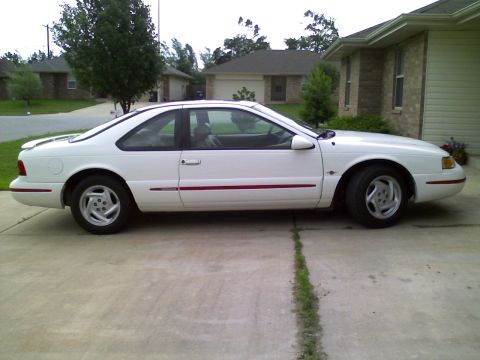1995 Ford Thunderbird - Side view of a white coupe with a red pinstripe detail.