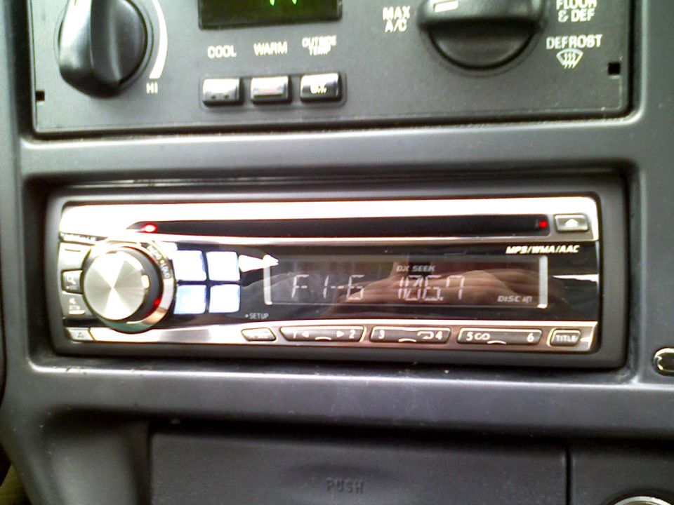 Car interior showing an aftermarket stereo display with radio station 106.7 FM
