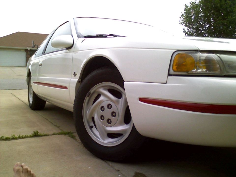 White 1995 Ford Thunderbird coupe parked in a driveway. Close-up on the front passenger side