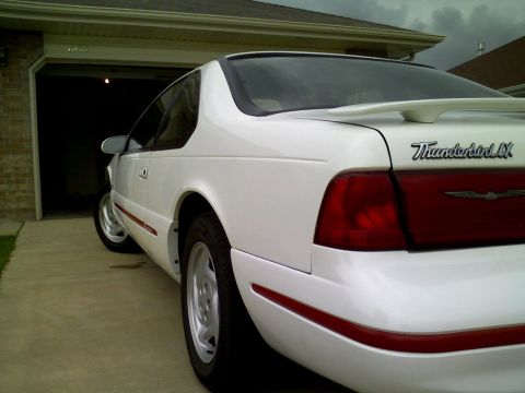 1995 Ford Thunderbird - White 1995 Ford Thunderbird LX coupe with a spoiler, seen from the rear quarter angle in a driveway.