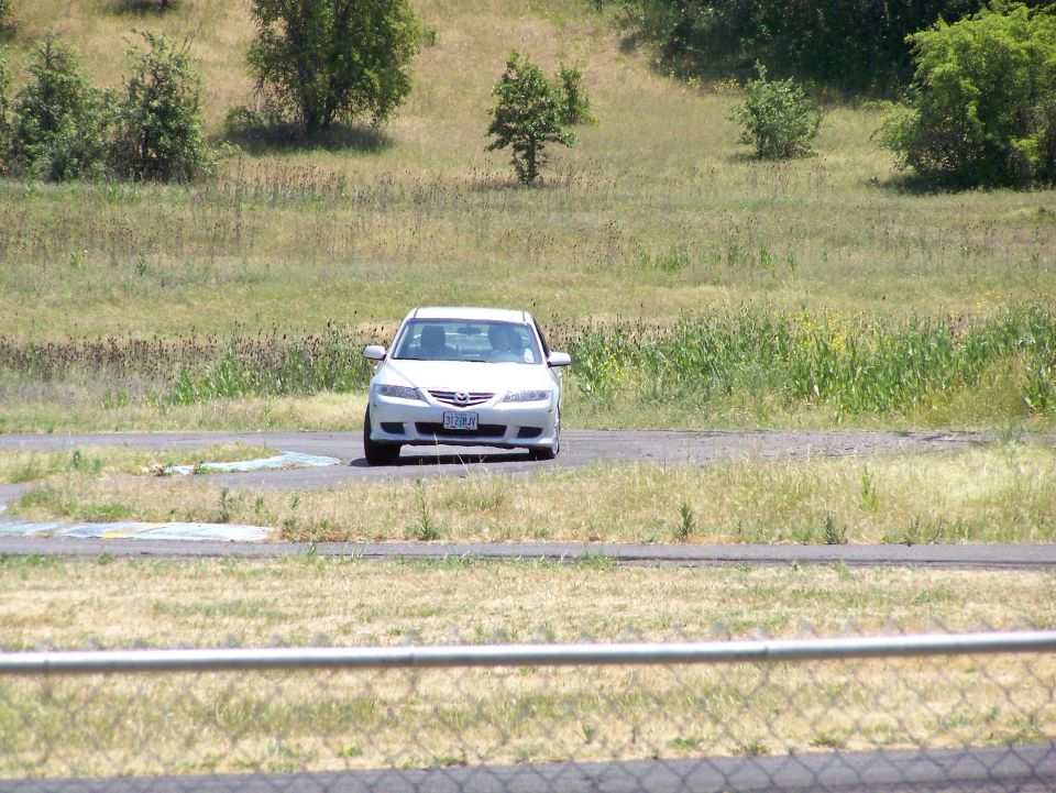 White sedan with a license plate reading "572 JHA" driving on a paved surface