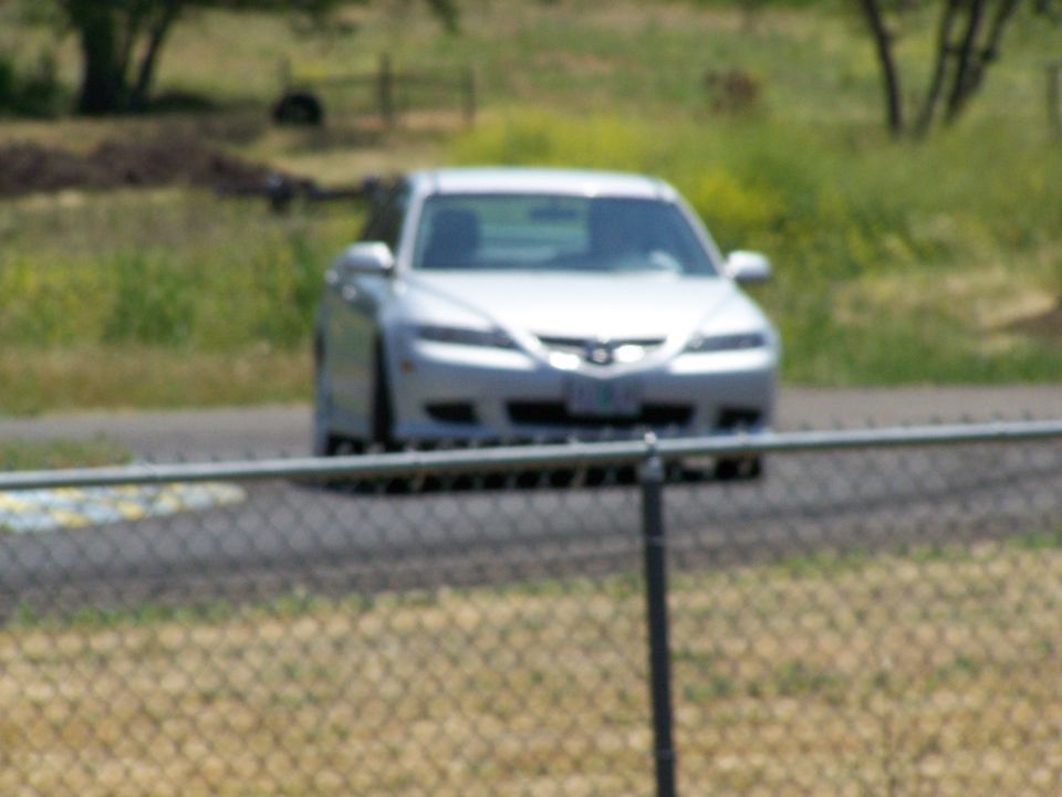 Silver sedan, front view, behind a fence