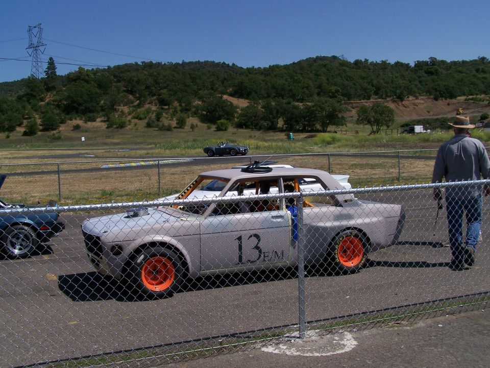 Light gray race car with orange wheels and number 13 on the door, viewed from the front-right