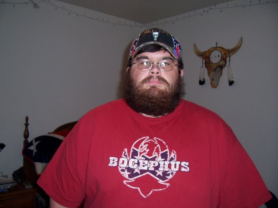 Man with beard and glasses wearing a Bocephus t-shirt and confederate flag hat