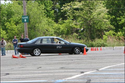 2001 Mercury Grand Marquis - A black sedan navigates a course marked by orange cones, with spectators watching nearby.