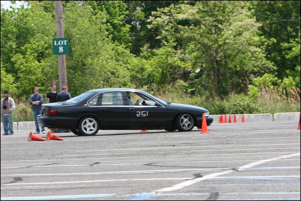 Black sedan with number 251 on the door, driving around cones on a track