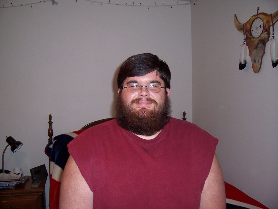 Man with a full beard and glasses wearing a maroon t-shirt