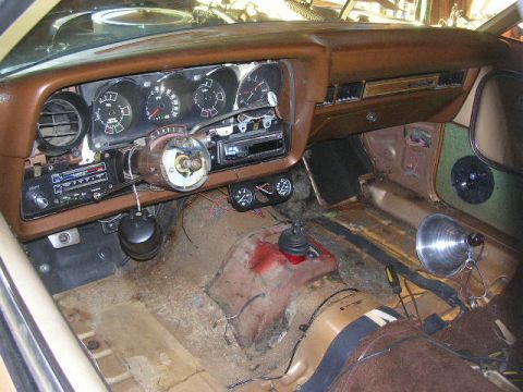 1975 Ford Ranchero - The interior of a 1975 Ford Ranchero shows a brown dashboard, aftermarket radio, and a floor shifter.