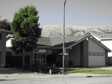 1996 Ford Bronco - A suburban house with a tree and garage, set against a backdrop of rolling hills.