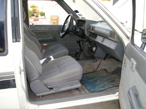 1986 Toyota Hilux - The interior of this pickup truck, likely from the 1980s, shows its age with worn seats and dashboard elements.