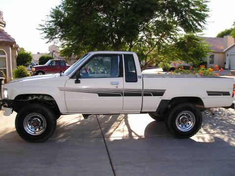 1986 Toyota Hilux - Side view of a white pickup truck with custom graphics, parked outside a house.