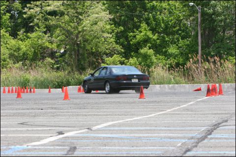2001 Mercury Grand Marquis - A black sedan navigates an autocross course marked by orange cones on a paved lot.