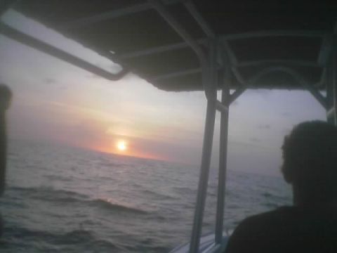 1989 Ford Bronco - A person watches the sun set over the water from a boat.