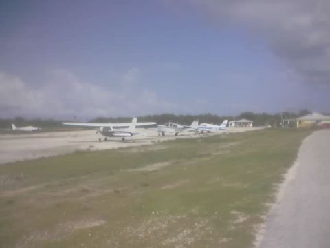 1989 Ford Bronco - Small aircraft are lined up on an airport tarmac under a partly cloudy sky.