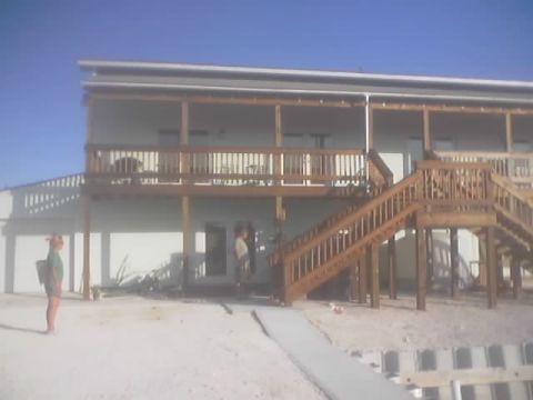 1989 Ford Bronco - A scene a house with a prominent wooden deck and stairs, under a clear blue sky.