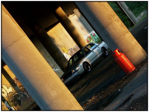 1998 Ford Crown Victoria - A silver 1998 Ford Crown Victoria is parked under a bridge, bathed in golden hour light.