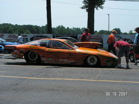 1988 Ford Mustang - Drag racing car with custom graphics and large hood scoop at a track event.