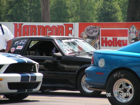 1988 Ford Mustang - Three Mustangs lined up at a drag strip, with 'Hardcore' and 'Holley' banners in the background.