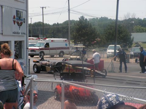 1988 Ford Mustang - A dragster and other vehicles are on the race track at a drag strip event.