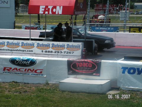 1988 Ford Mustang - A 1988 Ford Mustang is parked at a drag strip with sponsors banners visible.