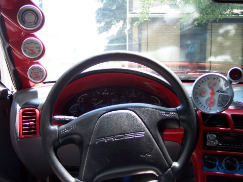 1994 Ford Probe - The interior of a 1994 Ford Probe is shown, a steering wheel with the car's name and several aftermarket gauges.