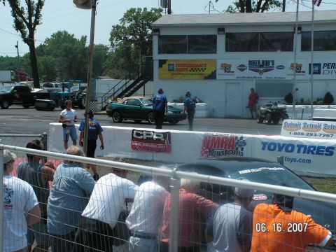 1988 Ford Mustang - A green convertible is seen at a drag strip event with spectators in the foreground.