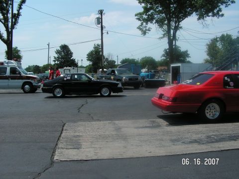 1988 Ford Mustang - A black 1987 Ford Mustang is parked on asphalt next to an ambulance and other vehicles.