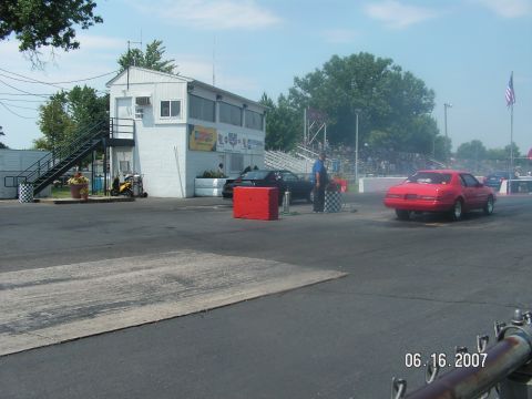 1988 Ford Mustang - A red 1987 Ford Mustang is seen from the rear on a drag strip, with a crowd in the background.