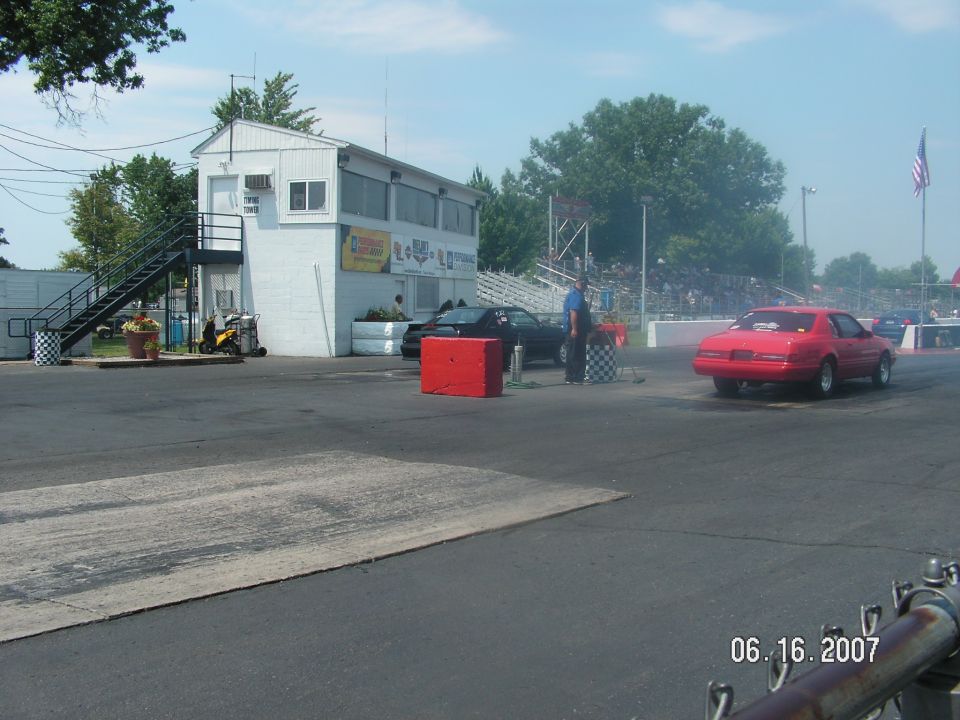 Red 1987 Ford Mustang on drag strip, rear view