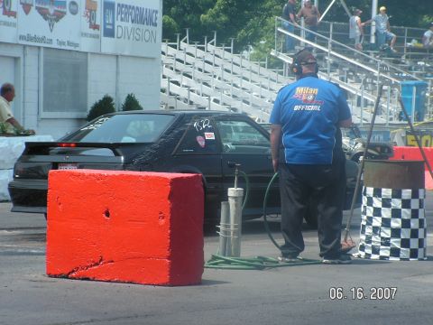 1988 Ford Mustang - A black 1988 Ford Mustang is seen at a drag strip with an official in the foreground.