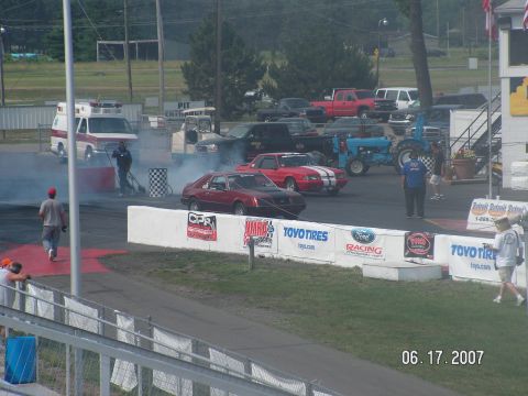 1988 Ford Mustang - Drag race in progress with two cars on the track and an ambulance nearby.